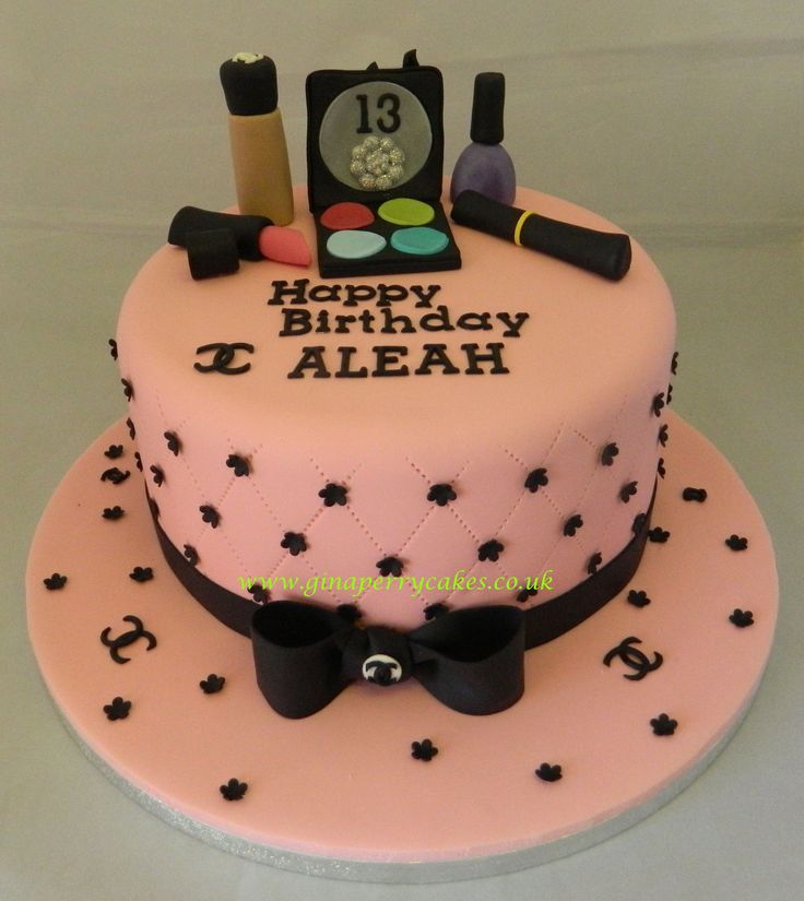 a pink birthday cake with black decorations on it