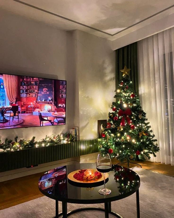 a living room with a christmas tree in the corner and a flat screen tv on