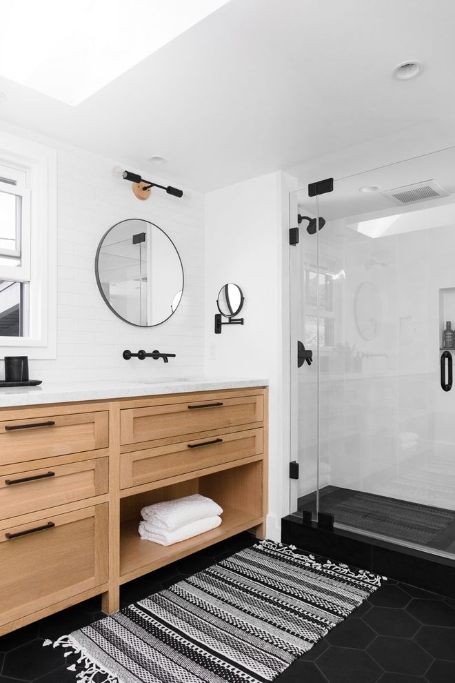 a bathroom with black and white rugs on the floor, wooden cabinets and mirror