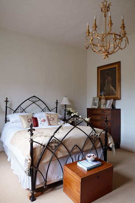 a bedroom with a bed, dresser and chandelier