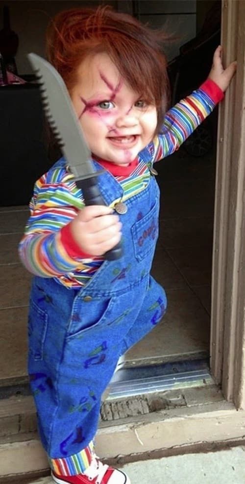 a young child dressed in clown makeup holding a large knife