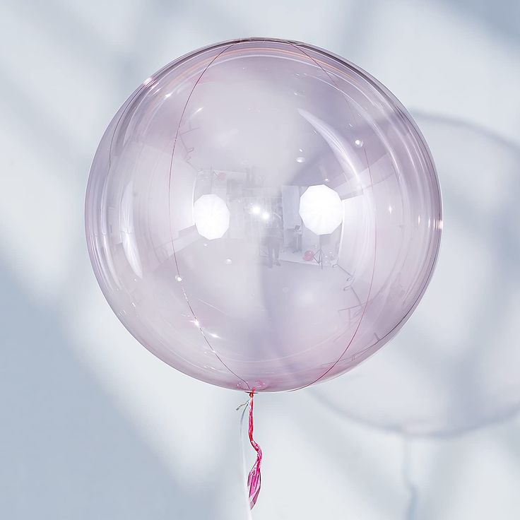 a clear balloon with red string hanging from it's end, on a white background