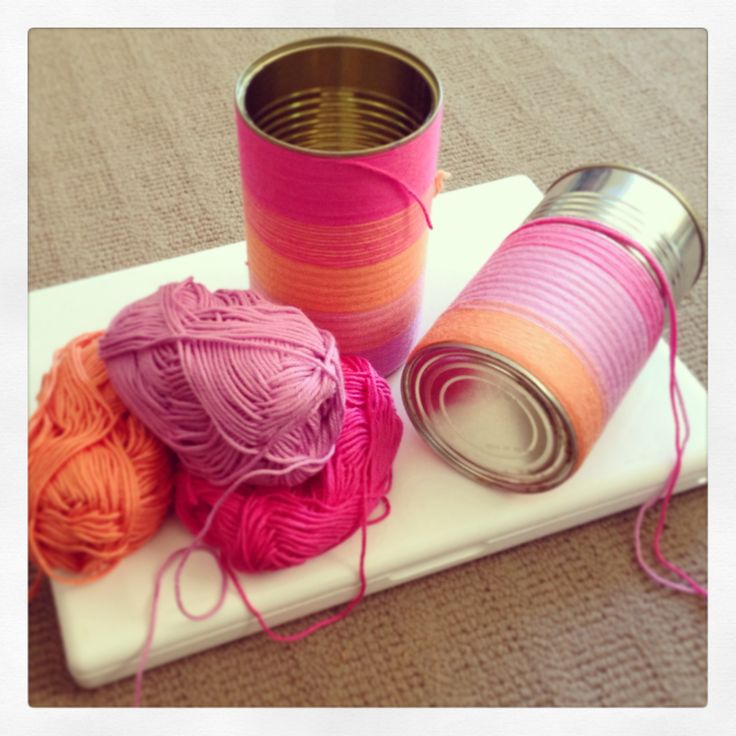 yarn and tin can sitting on top of a white tray with pink, orange, and yellow yarn