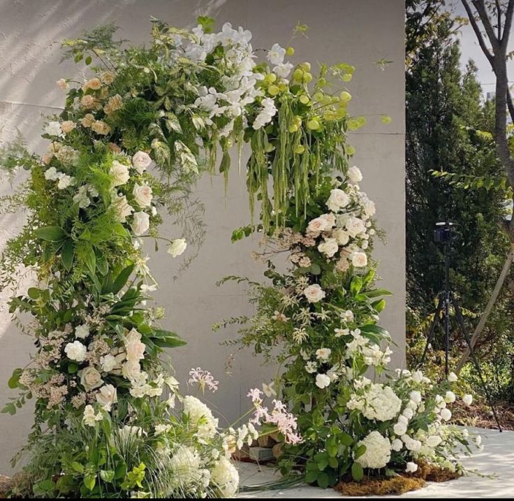 an outdoor wedding arch decorated with flowers and greenery