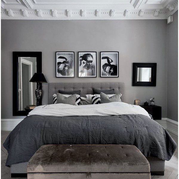 a bedroom with gray walls and pictures on the wall above the bed, along with a bench