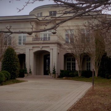 a large house with trees in front of it and a walkway leading to the entrance