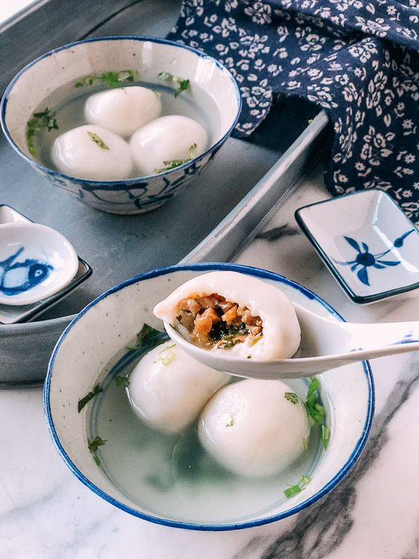 two bowls filled with food on top of a marble counter next to silver spoons