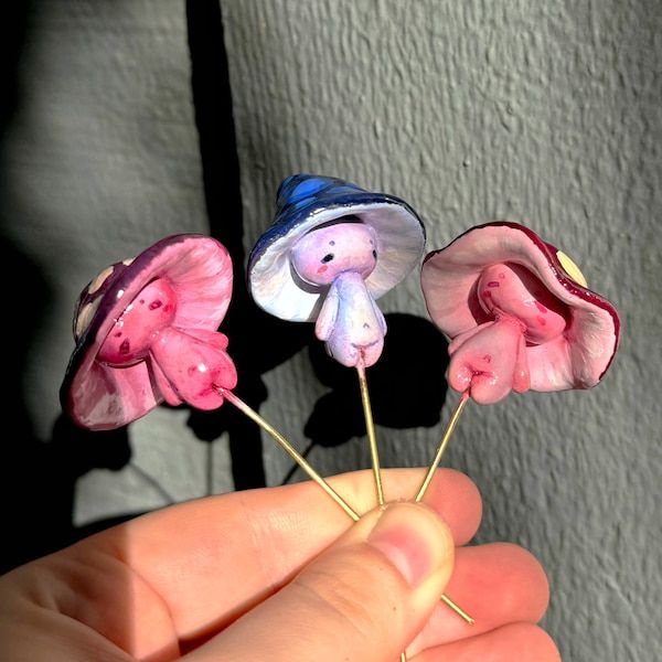 three small pink and blue flowers on top of each other in someone's hand