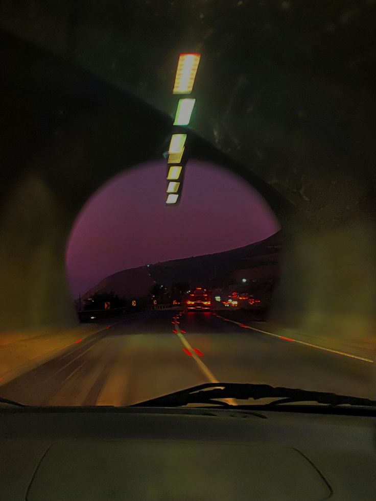 the view from inside a car looking out at an overcast sky and distant city lights