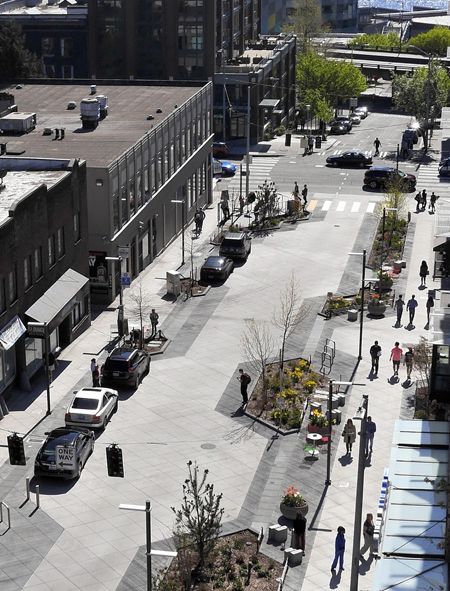 an aerial view of a city street with people walking and cars parked on the road