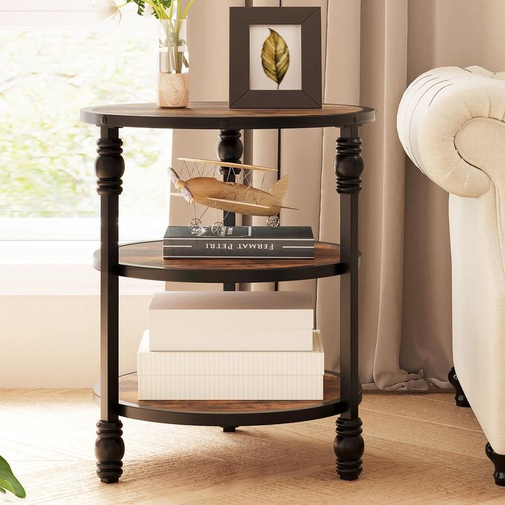 a corner table with books and vases on it next to a couch in a living room