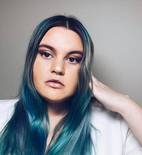 a woman with blue and green hair is posing for the camera while wearing a white shirt