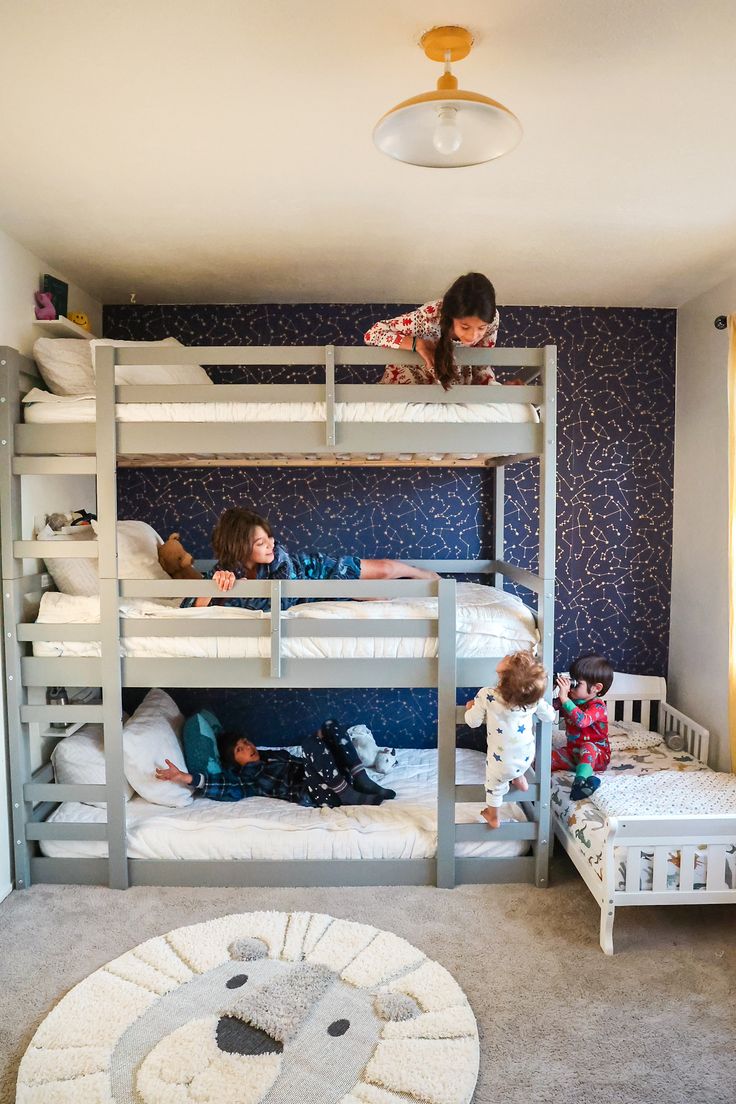 two children are laying on bunk beds in a room with blue wallpaper and carpet