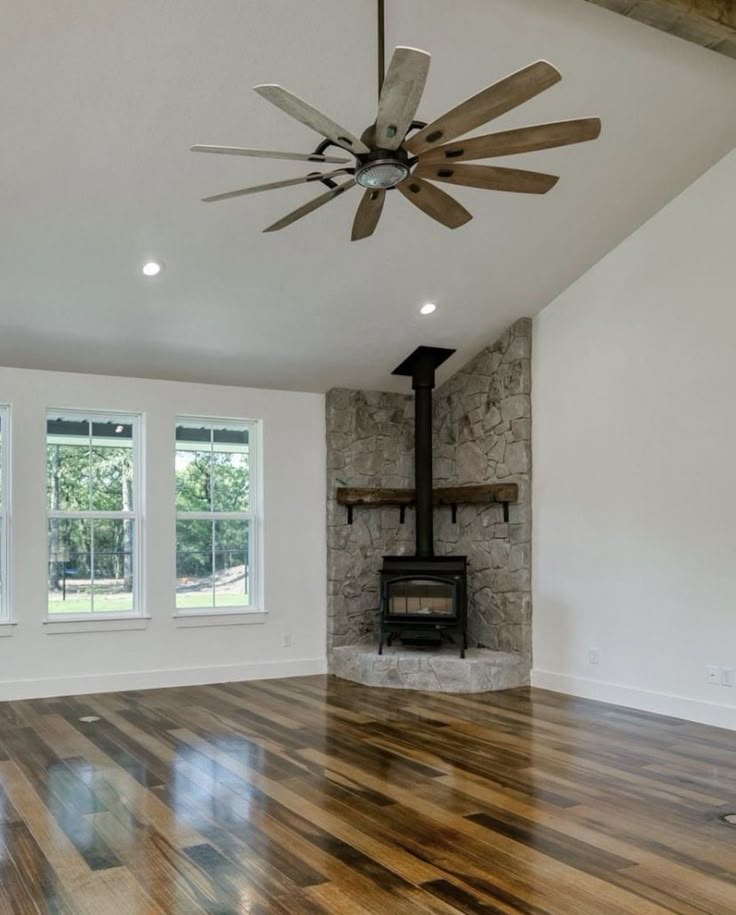 an empty living room with wood floors and a ceiling fan in the middle of the room