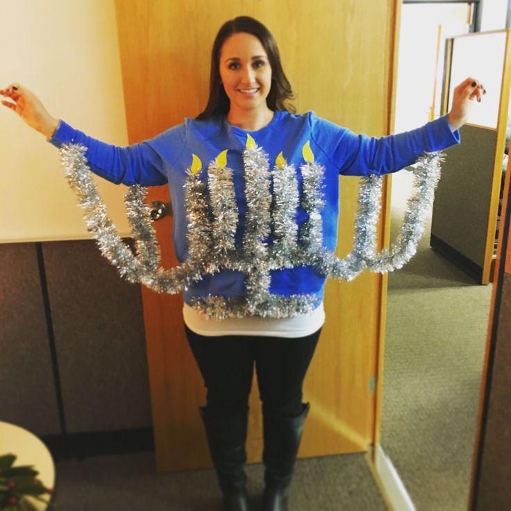 a woman is standing in an office with her arms out and christmas decorations on her sweater