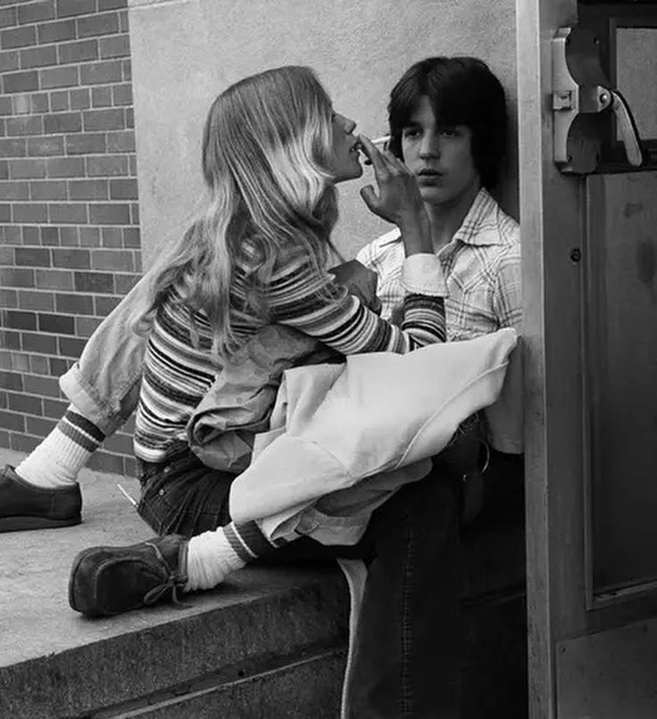 two people sitting on the curb talking on their cell phones