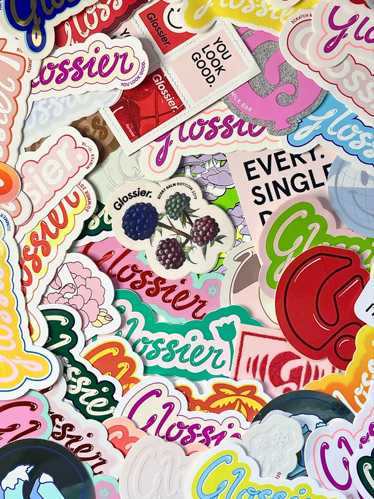 many different stickers and decals are on the table top, including raspberries