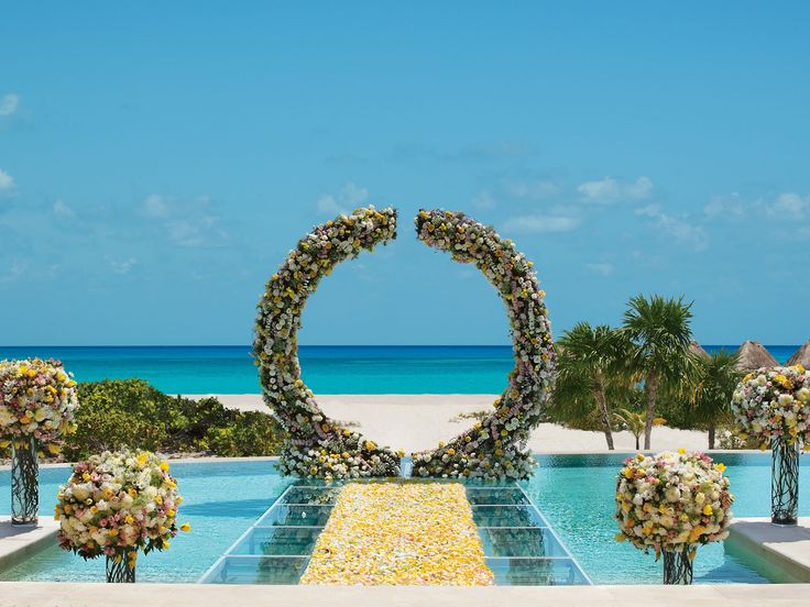 an outdoor wedding setup with flowers arranged in the shape of a circle on top of a pool