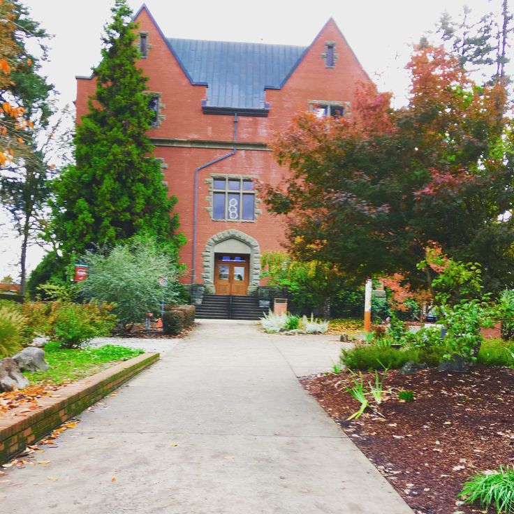 a large red brick building surrounded by lots of trees and plants in front of it