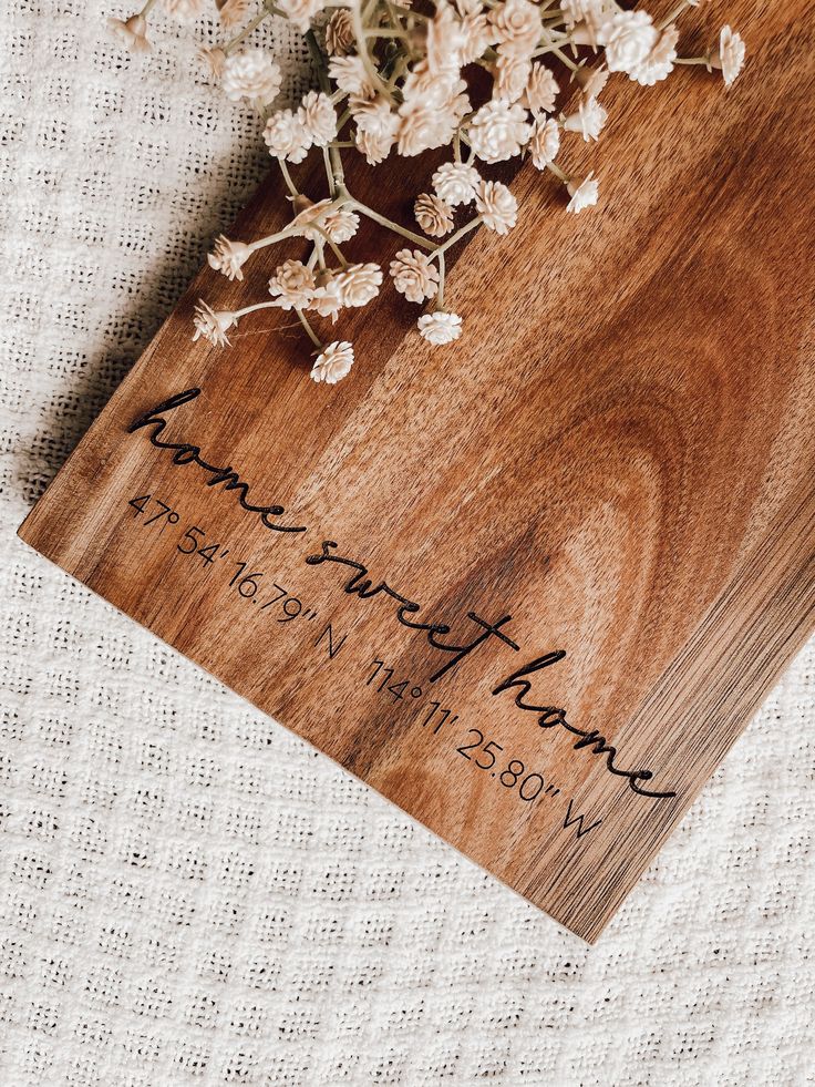 a wooden cutting board with flowers on top of it next to a white table cloth