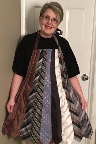 an older woman wearing a dress made out of ties, standing in front of a door