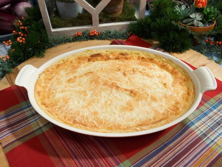 a casserole dish on a table with christmas decorations in the window behind it