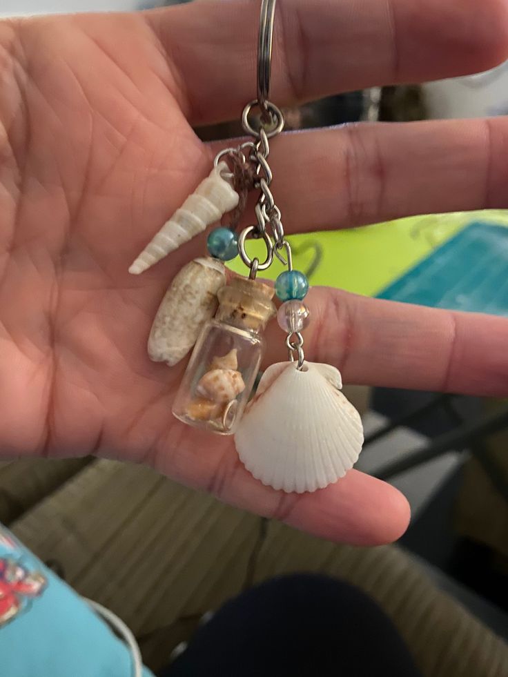 a person is holding two seashells in their hand with charms attached to them