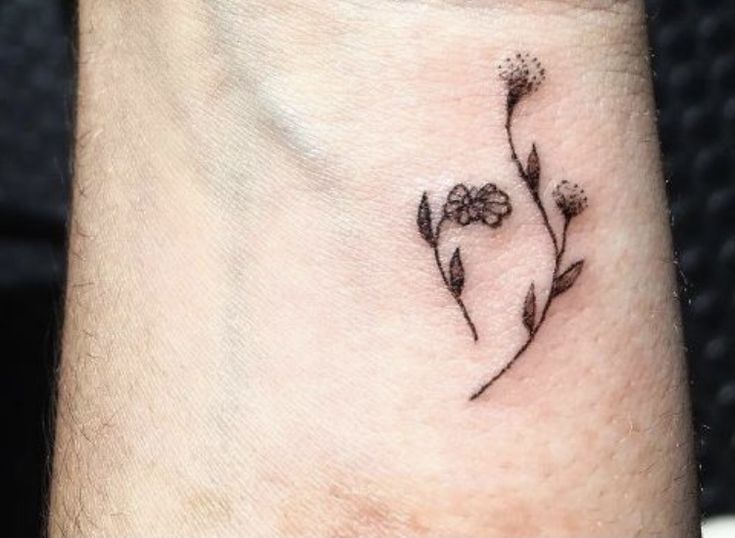 a small flower tattoo on the wrist