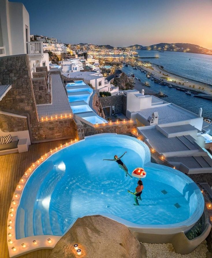 two people are swimming in an above ground pool with lights on the sides and water below