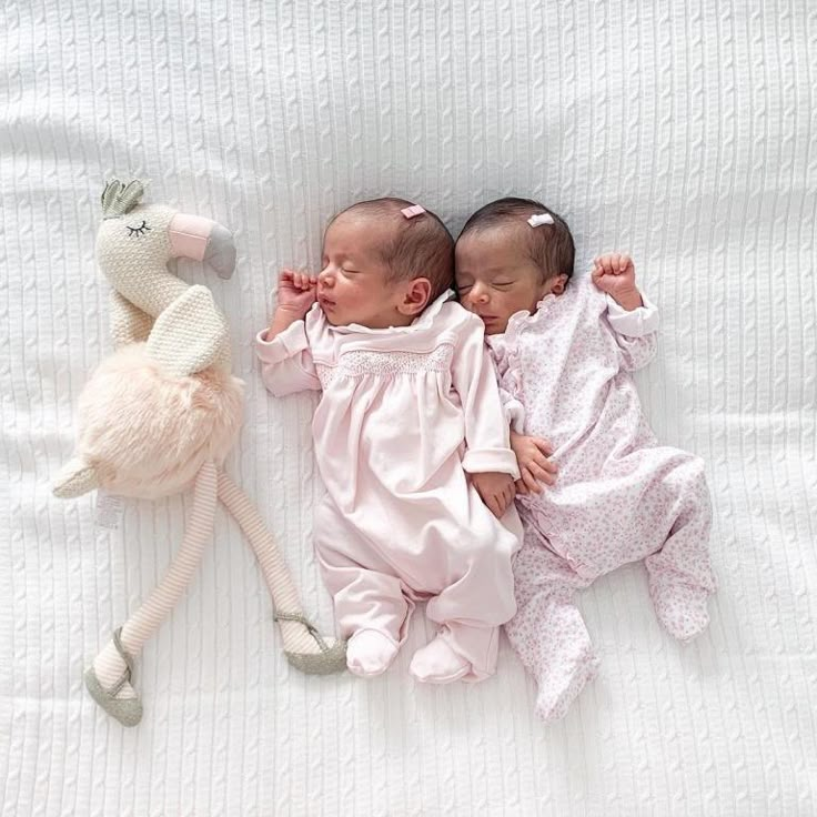 two babies laying next to each other on a bed