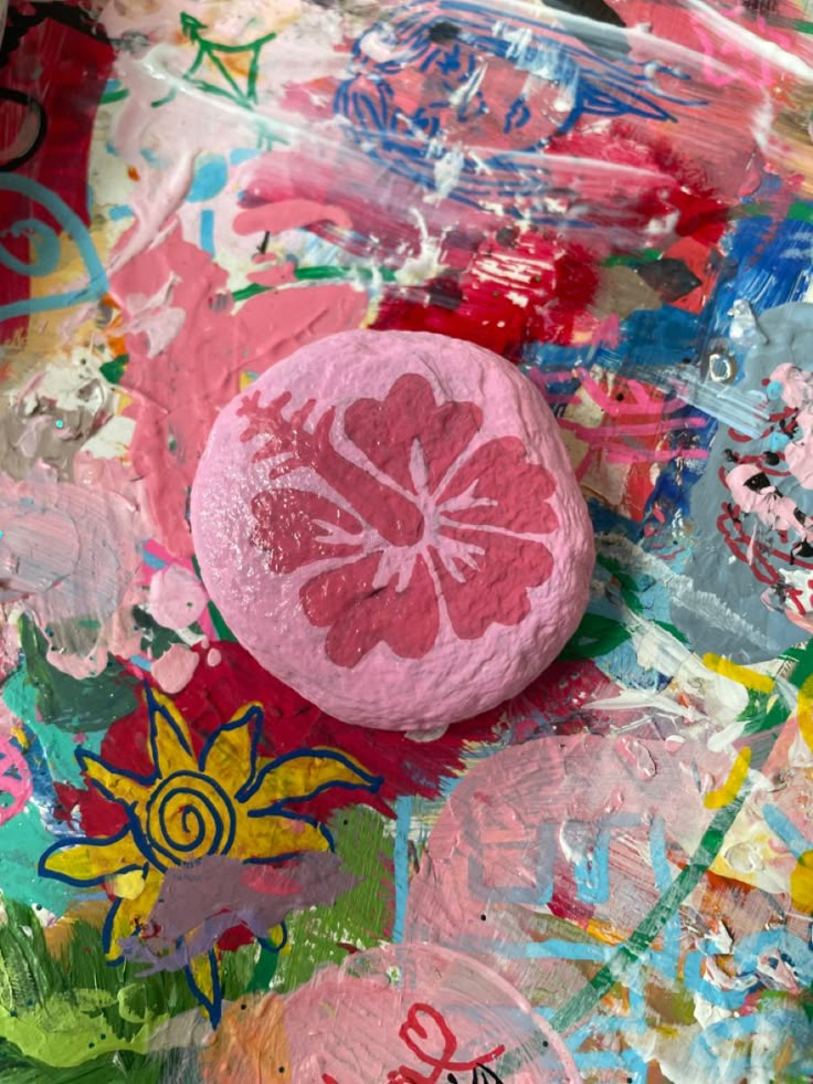 a pink button sitting on top of a piece of paper covered in lots of paint