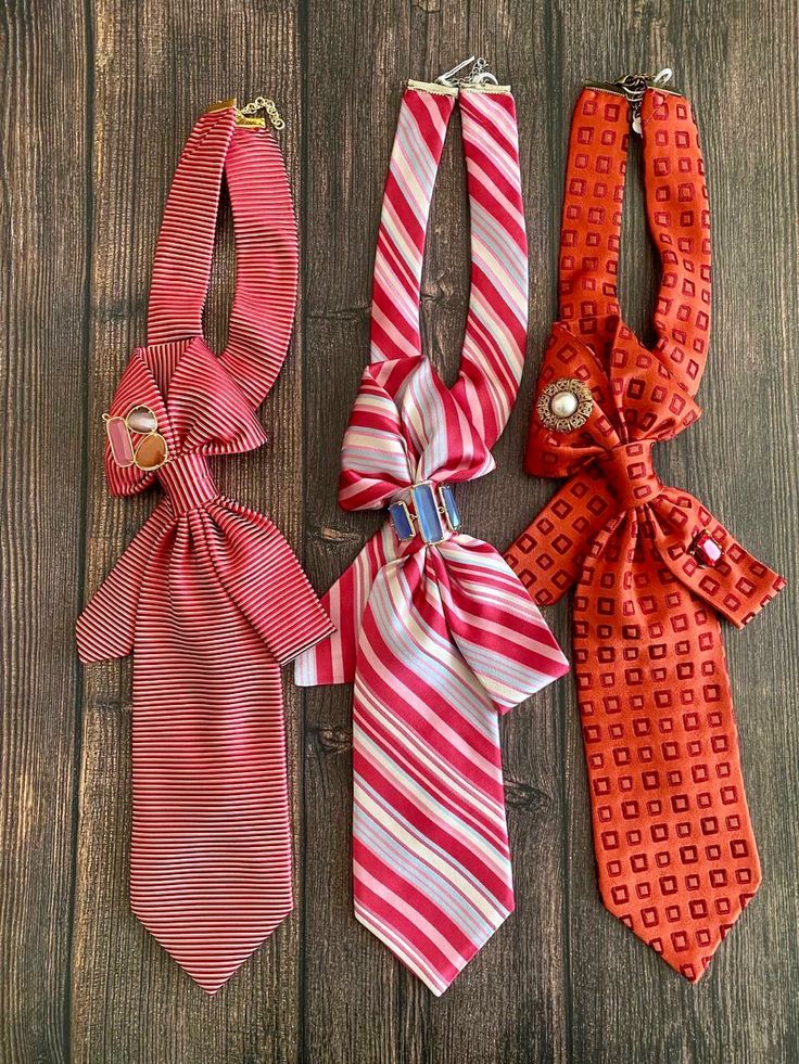 three ties are laid out on a wooden surface, one is red and the other is white