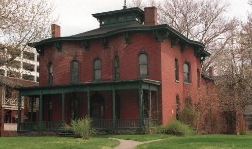 an old red brick house with green trim