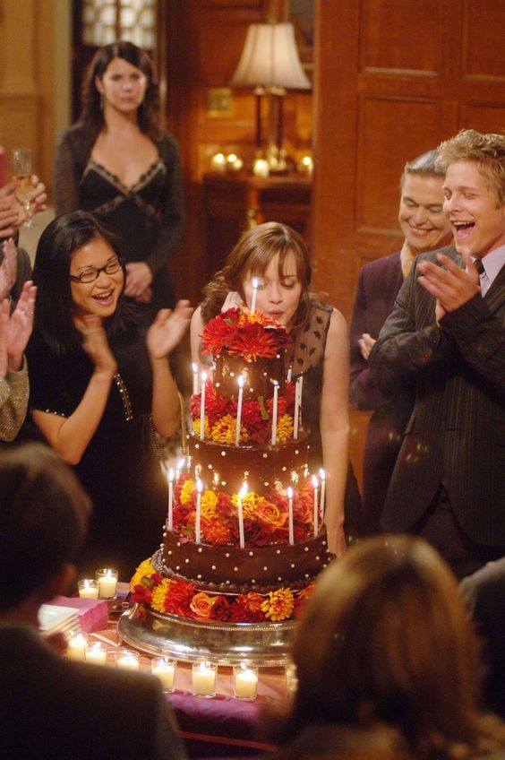 a group of people standing around a cake with candles on it