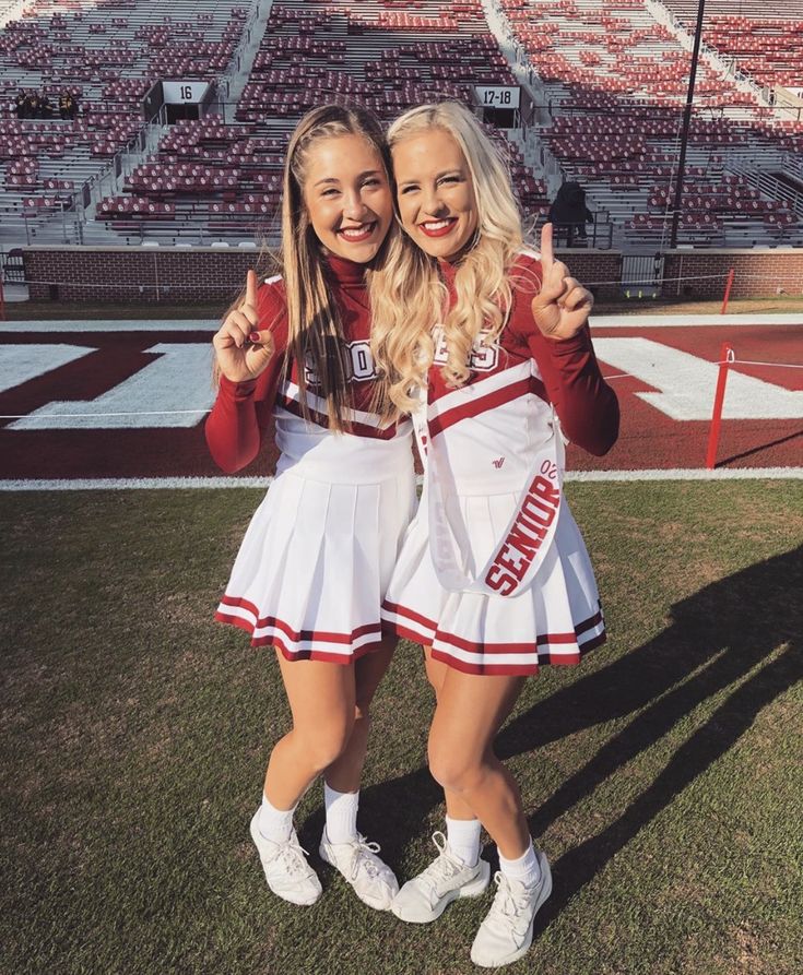 two cheerleaders giving the peace sign at a football game