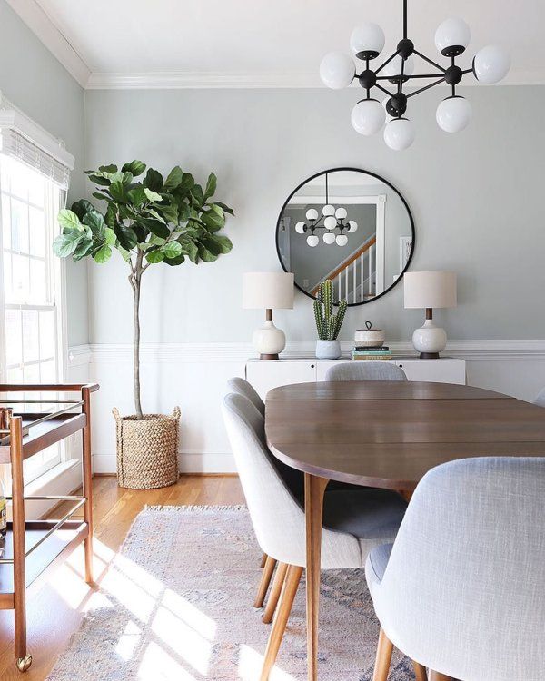 a dining room table with chairs and a mirror on the wall in front of it