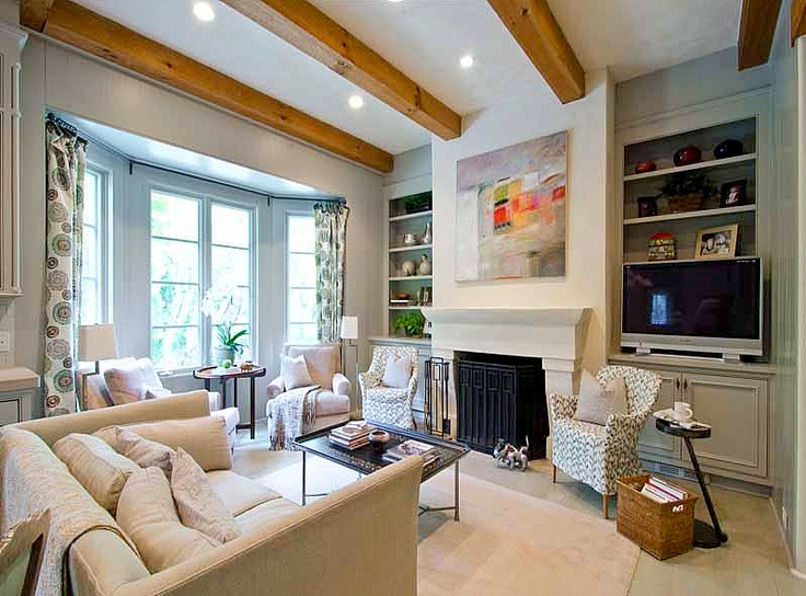 a living room filled with furniture and a flat screen tv mounted on the wall above a fireplace