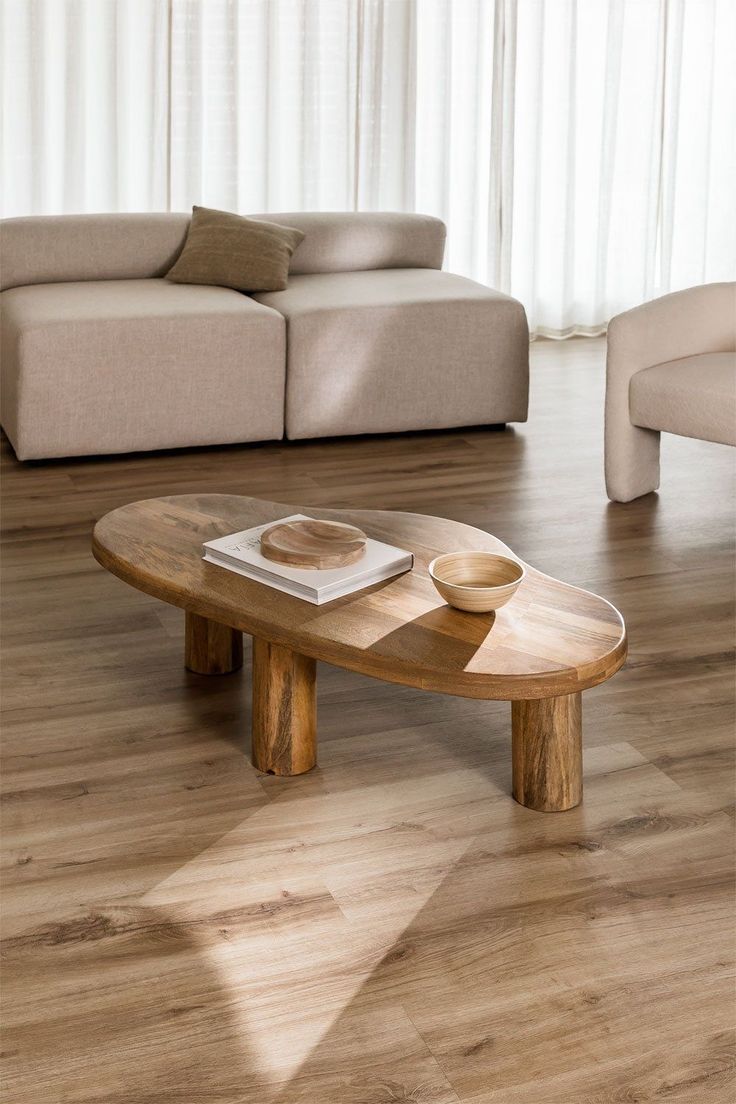 a wooden table sitting on top of a hard wood floor next to a white couch