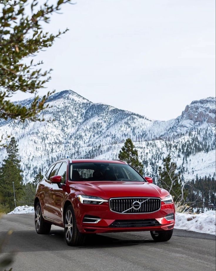 a red volvo car driving down a mountain road