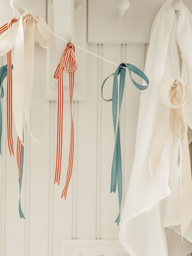 three ribbons hanging from a clothes line in front of a white wall and cupboards