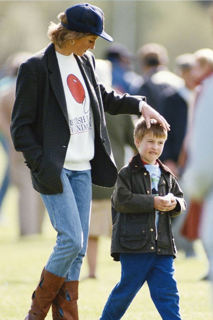 a woman walking next to a little boy on top of a field