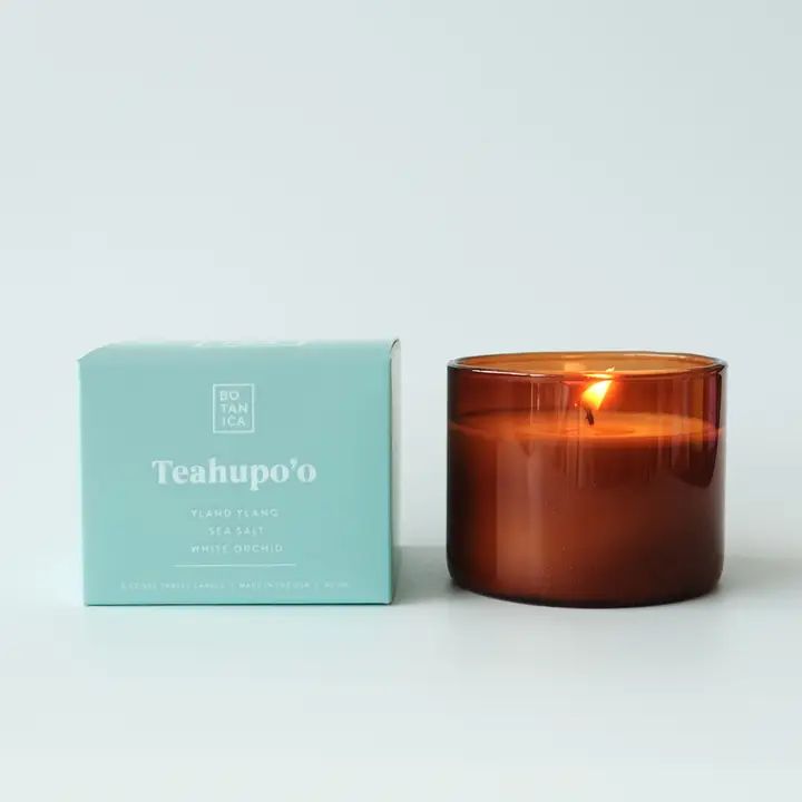 a candle sitting next to a box on a white surface with the words teacupo printed on it