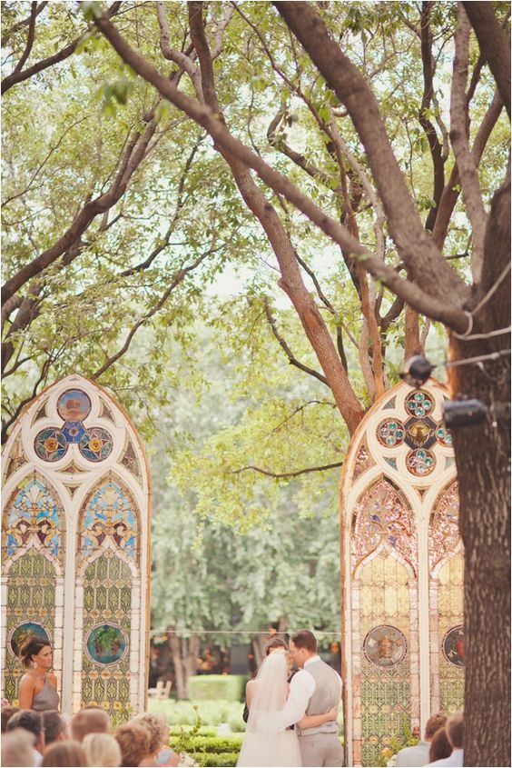 a bride and groom standing in front of stained glass windows at their wedding ceremony under the trees