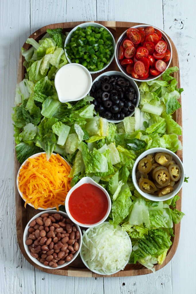 a platter filled with lettuce, beans, tomatoes and other toppings