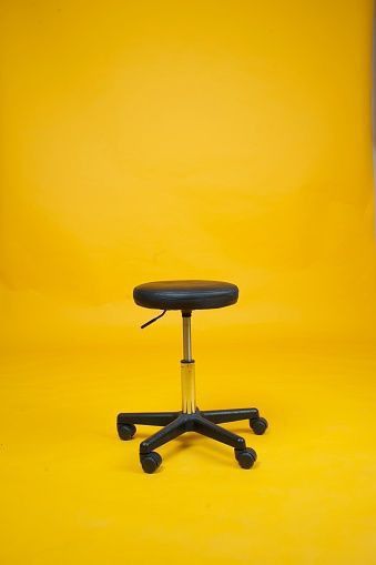 a black and yellow chair against a bright yellow background with the seat up in front of it