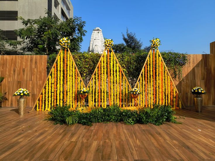 a wooden floor topped with lots of yellow flowers next to a tall white statue in the background