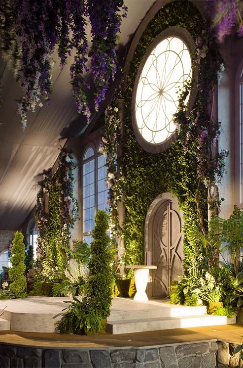 an indoor garden with flowers and greenery on the wall, surrounded by arched windows