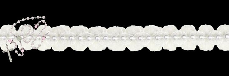 a long white beaded bracelet with beads and pearls on it's end, in front of a black background