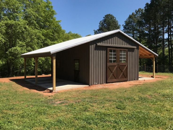 a small shed with a covered porch in the middle of a field next to trees