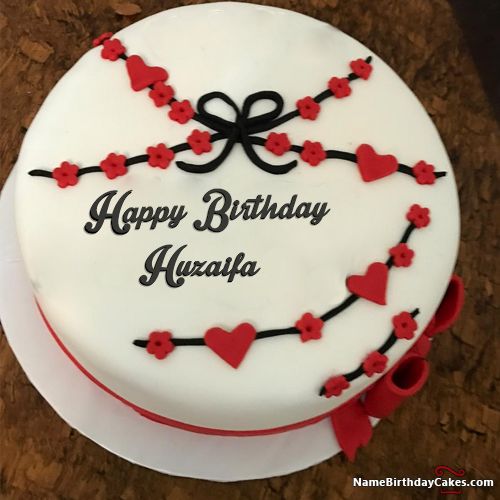 a birthday cake decorated with red and black hearts on a brown tableclothed surface